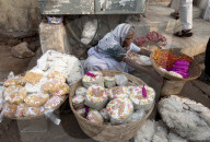 Woman in white sari, selling puja offerings from baskets in the street near the Hindu Jagannath temple dedicated to Lord Vishnu