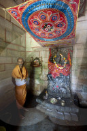 Hindu priest in saffron robes at the Radha Krishna shrine in tiny rural temple, Chaurasi, Prachi Valley, Odisha