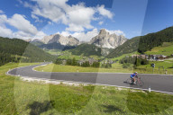 View toward Corvara and road cyclist, Alta Badia, Corvara, Dolomites, South Tyrol, Italy, Europe