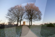 Broadway Tower framed by trees in winter frost at sunrise, Broadway, Cotswolds, Worcestershire, England, United Kingdom, Europe