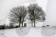Broadway Tower framed by bare trees in snow, Broadway, Cotswolds, Worcestershire, England, United Kingdom, Europe