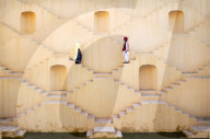A Hindu man and woman dressed in traditional clothing, walk down the maze steps of Panna Meena ka Kund Stepwell, Amer.