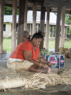 Woman with children weaving traditional mats in the town of Lufilufi on the island of Upolu, Samoa.