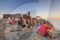 Tourists enjoying sunset at the lighthouse at Cabo de Sao Vicente, Sagres, Algarve, Portugal