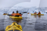 Expedition tourists kayaking in cold, snowy weather, with icebergs, Chilean Gonzalez Videla Station, Waterboat Point, Antarctica