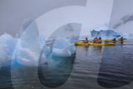 Expedition tourists kayaking in snowy weather, with blue icebergs, Chilean Gonzalez Videla Station, Waterboat Point, Antarctica