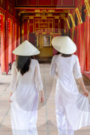 Vietnamese women in traditional Ao Dai dresses and Non La conical hats in the Forbidden Purple City of Hue