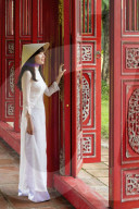 Vietnamese woman in traditional Ao Dai dress and Non La conical hat in the Forbidden Purple City of Hue