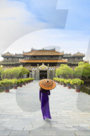 Woman in a traditional Ao Dai dress with a paper parasol in the Forbidden Purple City of Hue, A Unesco World Heritage Site