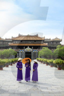 Women in a traditional Ao Dai dresses with a paper parasol in the Forbidden Purple City of Hue, A Unesco World Heritage Site