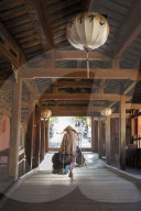 A woman carrying bags on a hod through the covered Japanese bridge in Hoi An