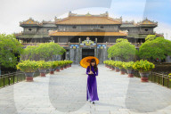 Women in a traditional Ao Dai dresses with a paper parasol in the Forbidden Purple City of Hue, A Unesco World Heritage Site