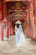 A woman in a traditional Ao Dai dress and Non La conical hat in the Forbidden Purple City of Hue, A Unesco World Heritage Site