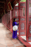 A woman in a traditional Ao Dai dress and Non La conical hat in the Forbidden Purple City of Hue, A Unesco World Heritage Site