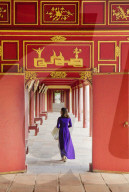 A woman in a traditional Ao Dai dress and Non La conical hat in the Forbidden Purple City of Hue, A Unesco World Heritage Site