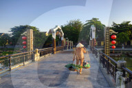 A woman carrying baskets on a yoke over the lantern bridge in Hoi An