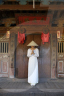 A Young woman in a Non La conical hat and a traditional Ao Dai dress in the historical centre