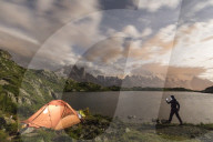 Hiker and tent on the shore of Lacs De Cheserys at night with Mont Blanc massif on background, Chamonix, Haute Savoie, France