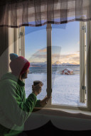 Man looks the snowy landscape from a window, Troms, Norway