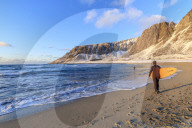 Surfer with surfboard on the beach, Unstad, Vestvagoy, Lofoten Islands, Norway