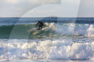 Surfer rides waves, Unstad, Vestvagoy, Lofoten Islands, Norway