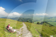 People on bench in the green valley of Ebenalp look towards Appenzell and Schwende, Appenzell Innerrhoden, Switzerland