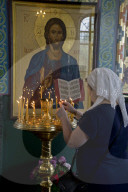 Woman lighting candles at a Russian Orthodox church service in Volgograd on the Volga river, Russia