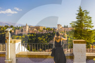 Woman taking a photo of Alhambra and Sierra Nevada mountains, Granada, Andalucia, Spain, Europe