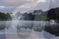 Early morning mist settles on the River Dee with boats and buildings reflected in the still water