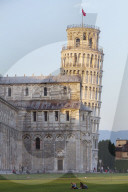 People relaxing on the lawns of the Campo dei Miracoli with the Cathedral and Leaning Tower behind.