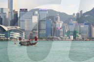 Traditional junk boat on Victoria Harbour with city skyline behind, Hong Kong