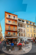 Traditional Provencal architecture in Antibes, Cote d'Azur, France. Tourists sit at a cafe on a street corner - wide angle