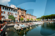 Boats on marina with tourists at cafes and restaurants at Desenzano del Garda, Lombardy, Italy on a summer day