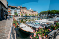 Boats on marina with tourists at cafes and restaurants at Desenzano del Garda, Lombardy, Italy on a summer day