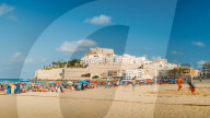 Crowded beach overlooking the medieval fort town of Peniscola, Spain