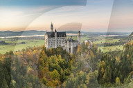 Neuschwanstein castle surrounded by coloured fir trees at sunset. Schwangau, Schwaben, Bavaria, Germany.