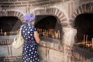 A female worshiper lights a candle outside the Biserica SfÃ¢ntul Anton in Bucharest, Romania.