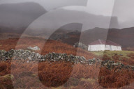 Traditional crofters cottage or shepherds bothy beneath An Sgurr Isle of Eigg Small Isles Inner Hebrides highlands Scotland UK