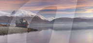 Beached fishing boat and view to a snow capped Ben Nevis from Loch Linnhe, Corpach, Highlands, Scotland