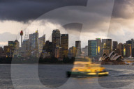 A ferry in Sydney Harbour at dusk with the Opera House and city skyline. New South Wales, Australia.