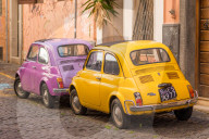 Two vintage Fiat 500s with Roma number plates parked in colourful backstreet of Trastevere, Italy, Lazio. Italy.