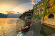 A boat of tourists stops to observe the sunset. Nesso, Province of Como, Como Lake, Lombardy, Italy, Europe.