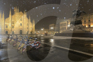 Parked bicycles in Piazza Duomo during a night snowfall. Milan, Lombardy, Northern Italy, Italy.