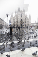 A person feeds pigeons in the Cathedral Square. Milan, Lombardy, Northern Italy, Italy.
