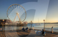People enjoying the view of Seattle Great Wheel from Waterfront Park in Seattle, Washington, USA