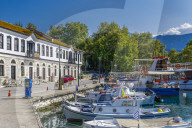 Thassos Greek island landscape view. Day view of Limenas town with green vegetation, traditional house and moored ships.
