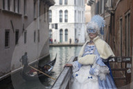 Lady in Venice Carnival costume with gondola in background. Venice, Veneto, Italy
