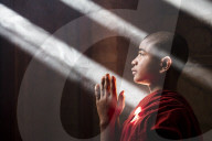 Young monk praying and covered with light beams in a temple in Bagan, Myanmar (Burma)
