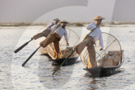 Three fishermen row with one leg at sunset on Inle Lake, Myanmar (Burma), Asia