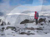 A winter walker on the summit of The Cairnwell in the Cairngorm National Park looking over to Carn a' Gheoidh